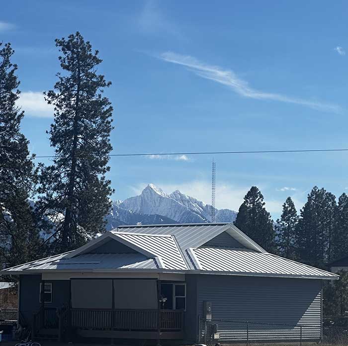 a beautiful standing seam metal roof with montana's famous mountains in the background