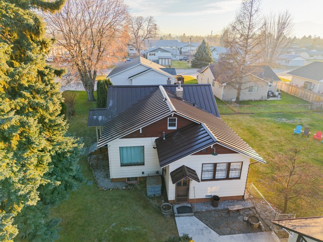Home with a dark metal roof at sunset, framed by trees and green lawns